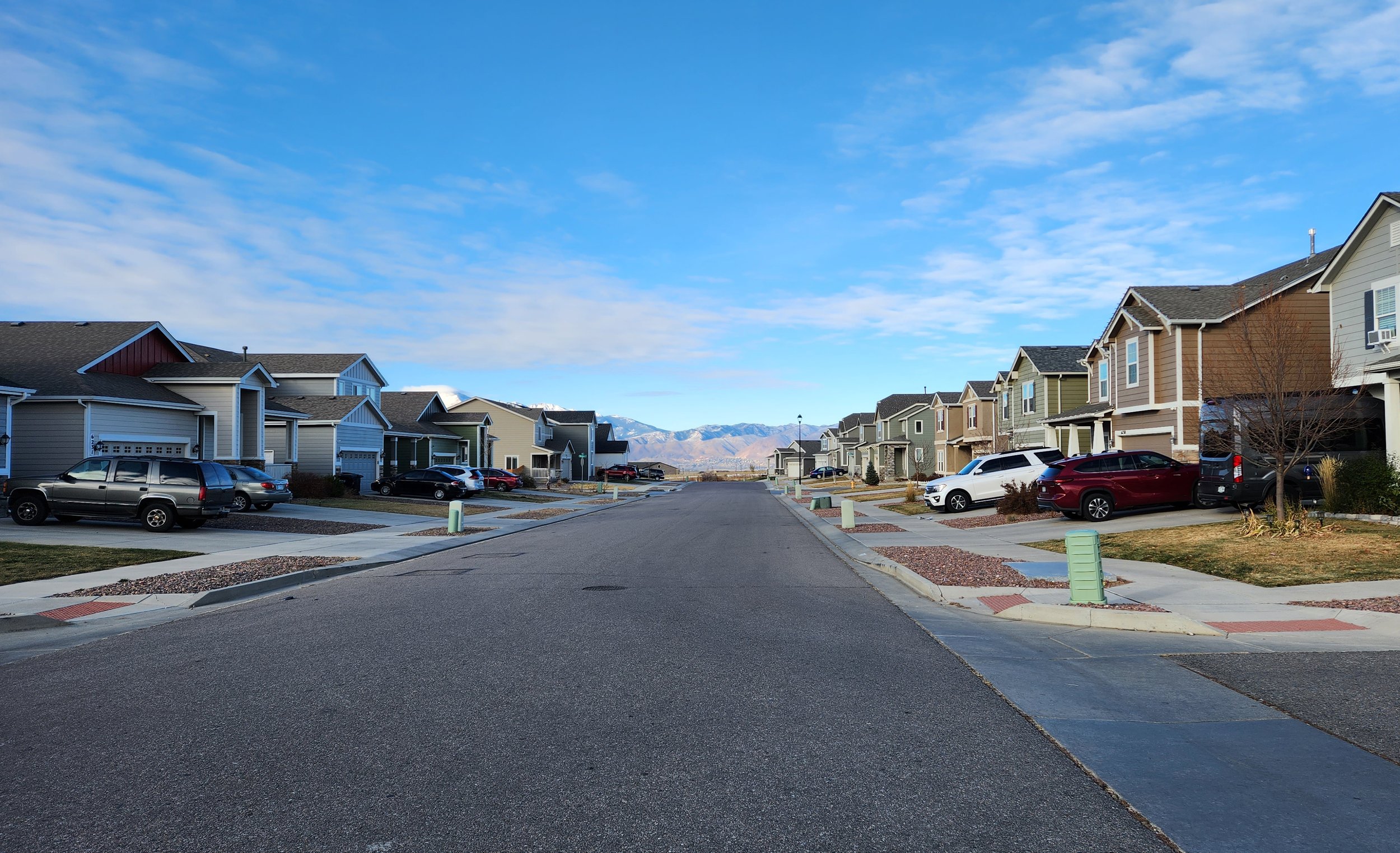 Homes line a stree with the Colorado mountains in the background.
