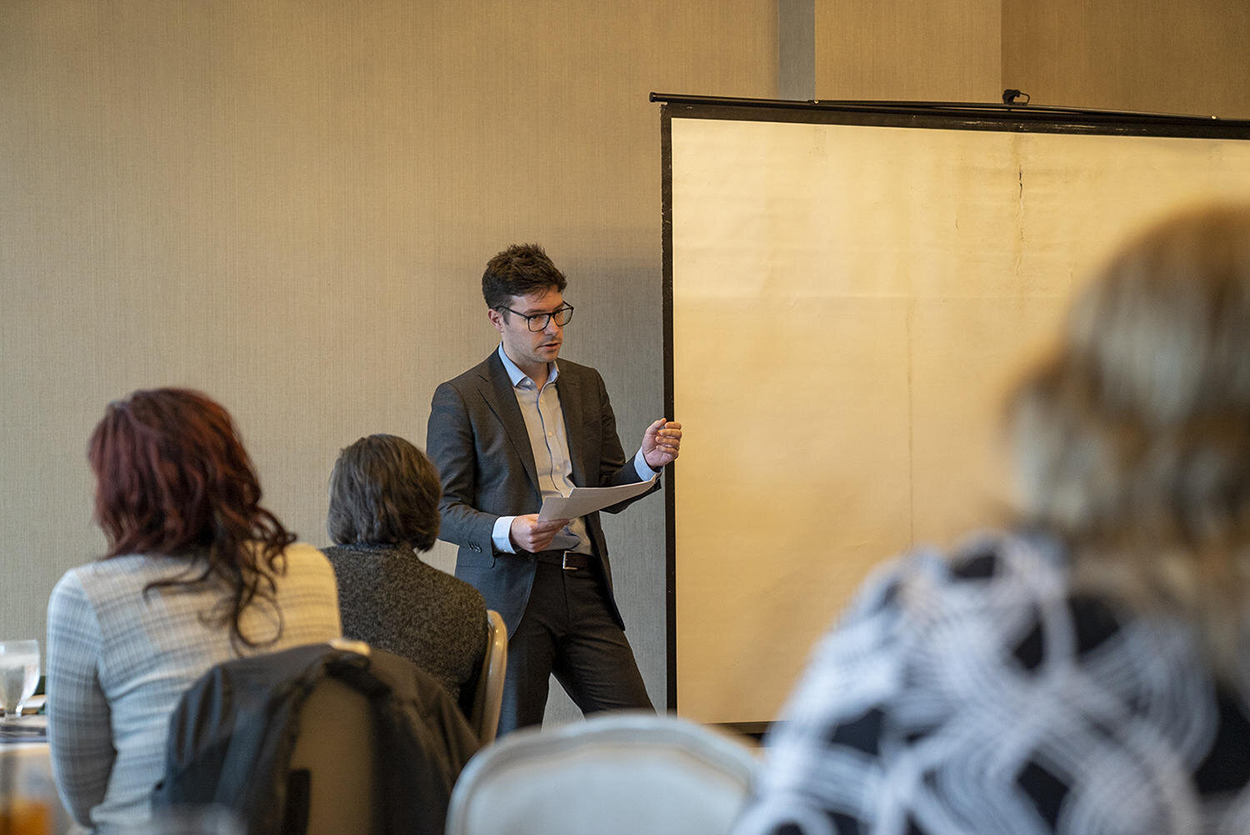 Lawyer Benjamin Wesselschmidt gives a presentation infront of dozens of people.