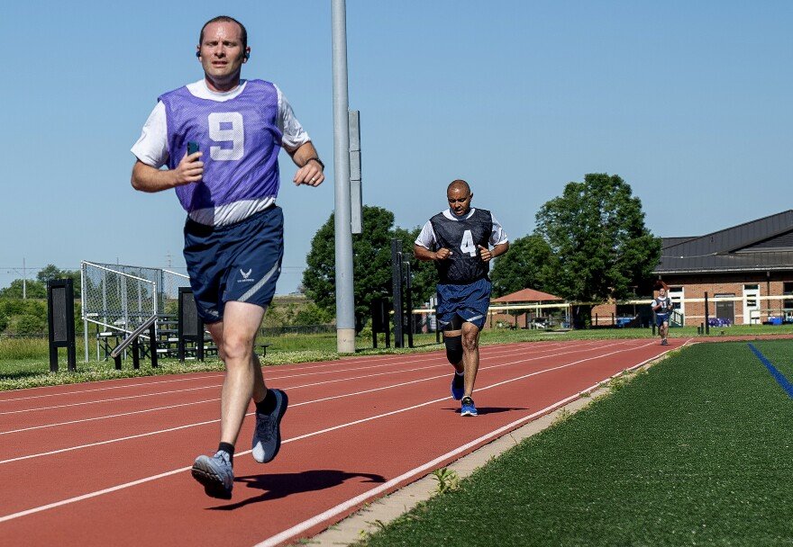 An airman in runs along an outdoor track.